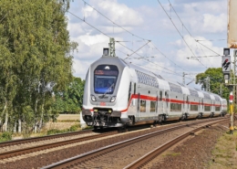 Intercity Zug auf Gleisen fahrend mit bäumen im Hintergrund