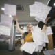 Gestresste Frau wirft Papier im Büro in die Luft