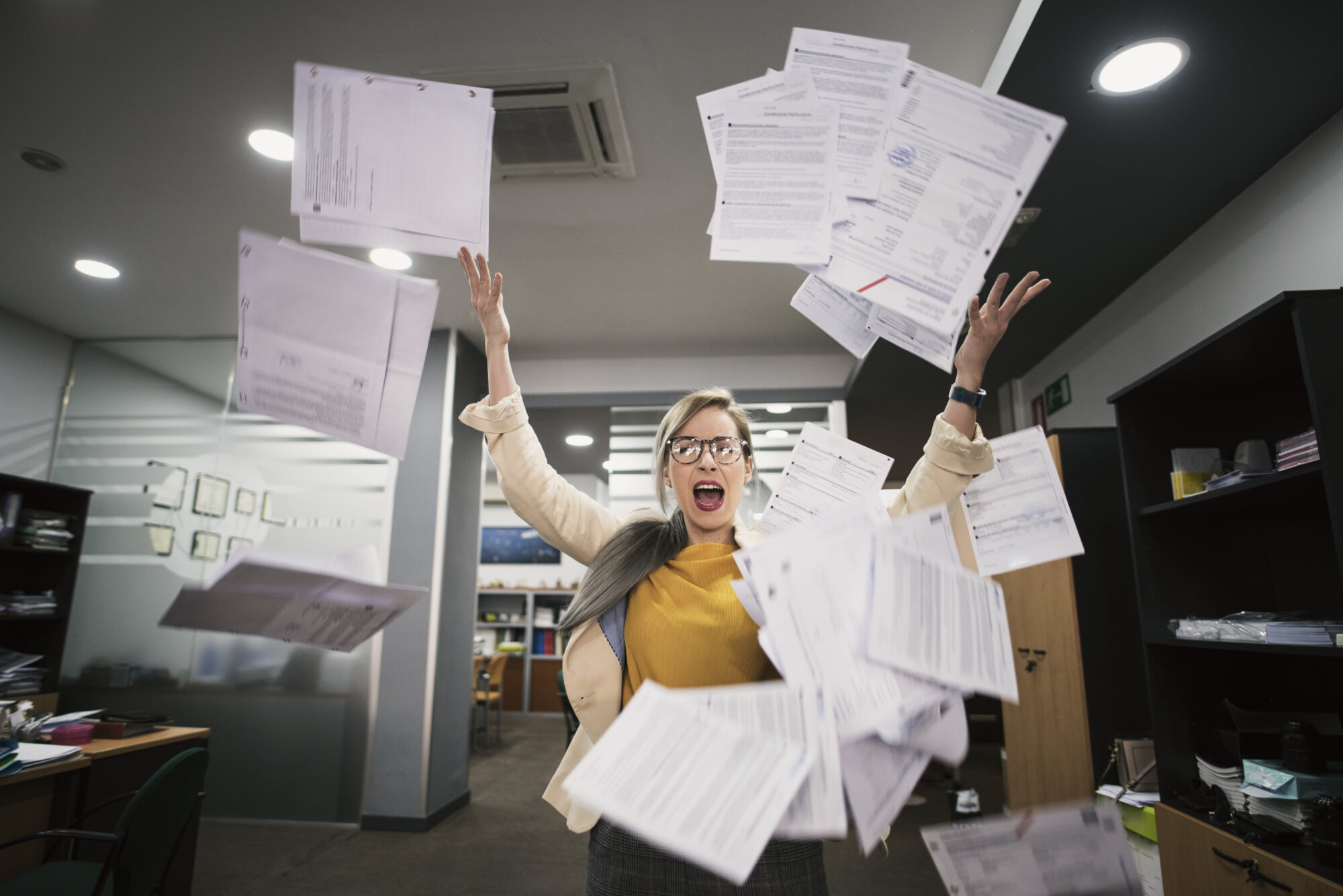 Gestresste Frau wirft Papier im Büro in die Luft